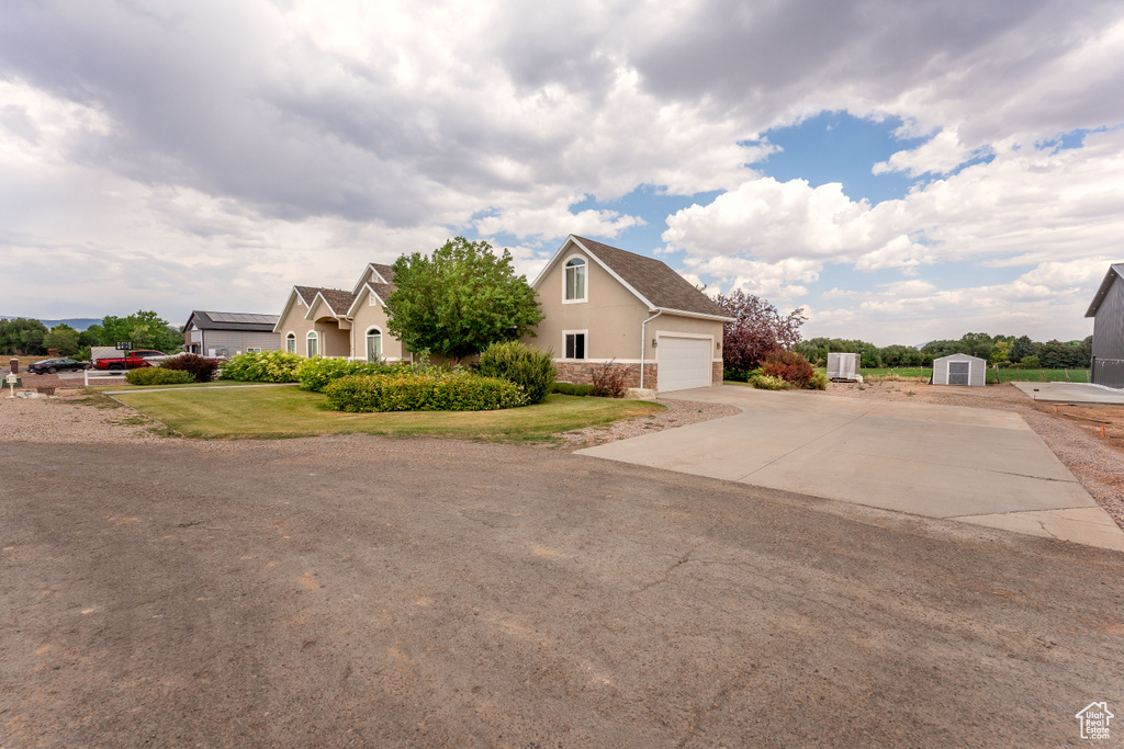 View of property exterior featuring a storage shed, driveway, stucco siding, stone siding, and an attached garage