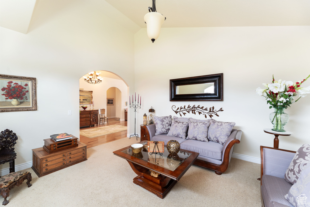 Carpeted living room featuring arched walkways and high vaulted ceiling