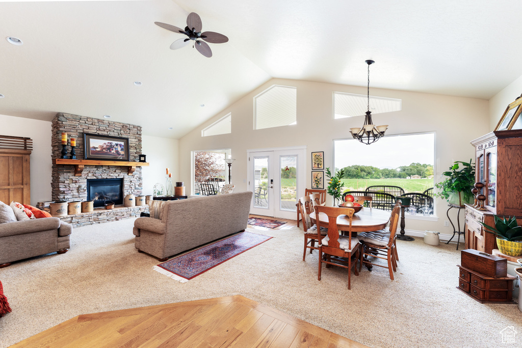 Living room with a fireplace, wood finished floors, healthy amount of natural light, a ceiling fan, and high vaulted ceiling
