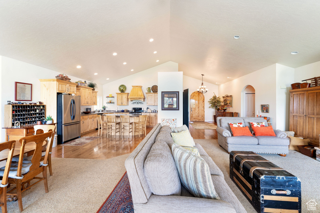 Living area with arched walkways, vaulted ceiling, light carpet, and recessed lighting
