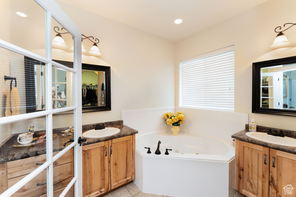 Bathroom with two vanities, a tub with jets, tile patterned flooring, and recessed lighting