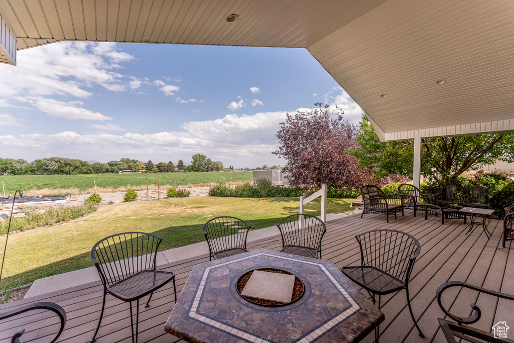 Wooden deck with a fire pit, a yard, and a view of countryside