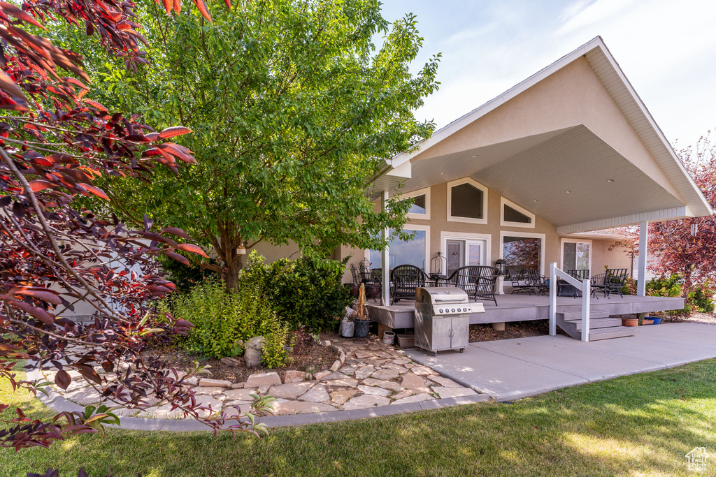 View of patio with a wooden deck and area for grilling