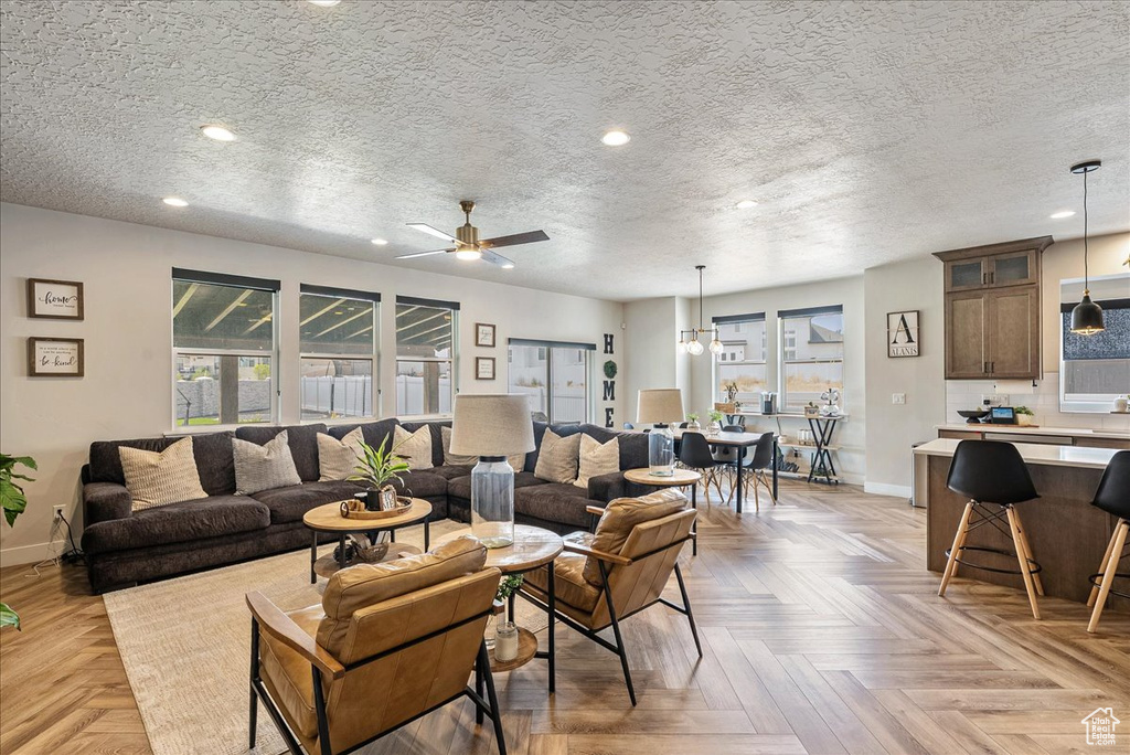Living room with a ceiling fan, a textured ceiling, and recessed lighting