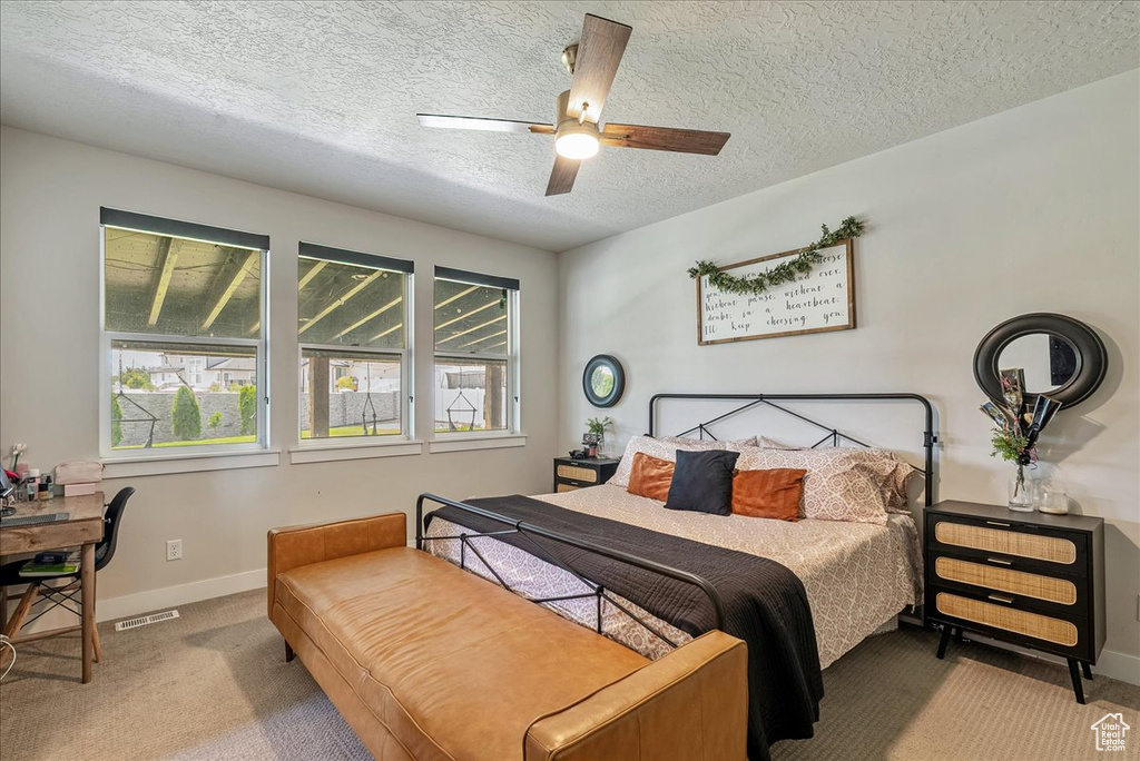 Carpeted bedroom with multiple windows, a textured ceiling, and ceiling fan