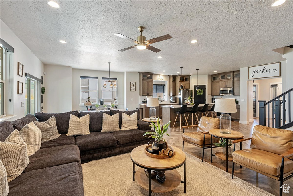 Living area with recessed lighting, ceiling fan, a textured ceiling, stairs, and a chandelier