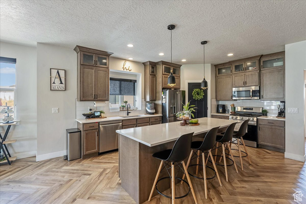 Kitchen with stainless steel appliances, tasteful backsplash, a center island, a breakfast bar area, and a textured ceiling