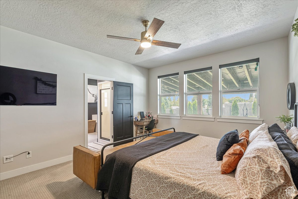 Bedroom with carpet flooring, a textured ceiling, a ceiling fan, and ensuite bathroom