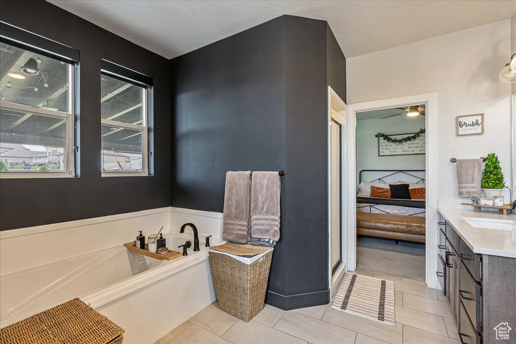Ensuite bathroom featuring a garden tub, vanity, tile patterned floors, and a textured ceiling