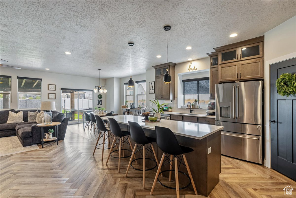 Kitchen featuring stainless steel fridge, open floor plan, a breakfast bar area, a kitchen island, and recessed lighting