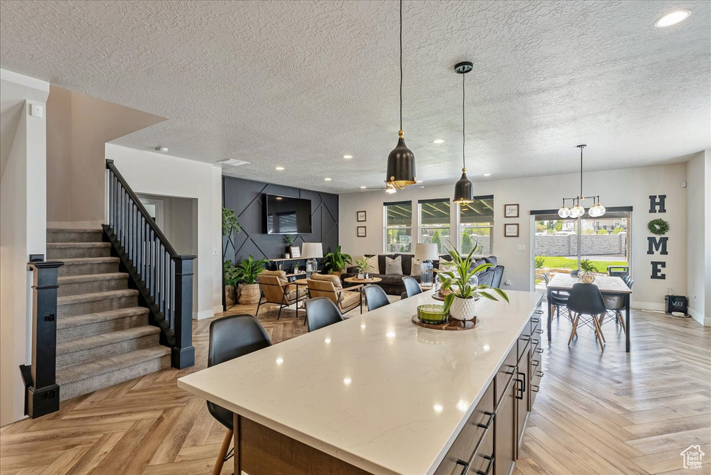 Kitchen with a center island, a textured ceiling, hanging light fixtures, recessed lighting, and a chandelier