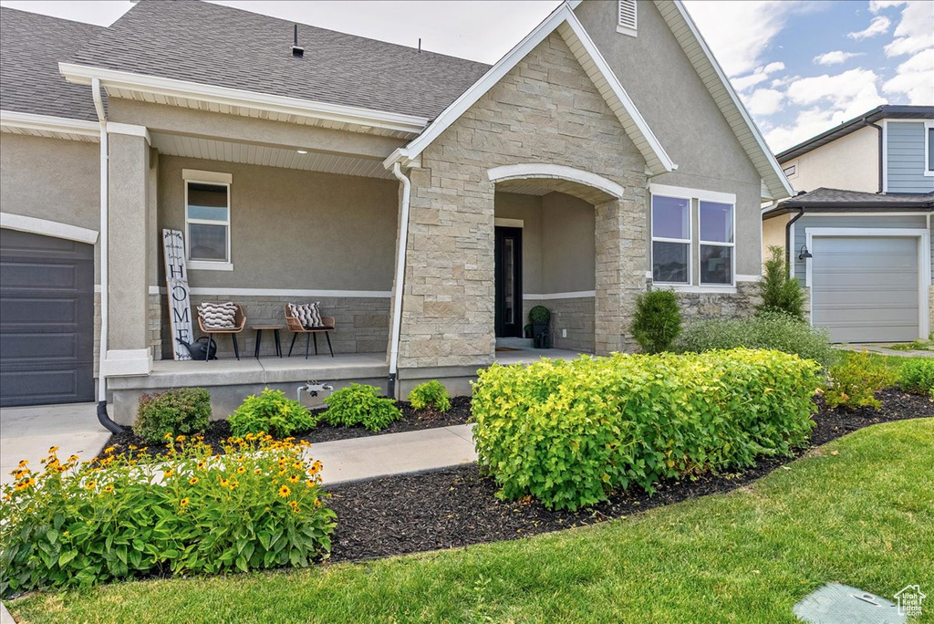 View of front facade with covered porch, stone siding, stucco siding, and roof with shingles