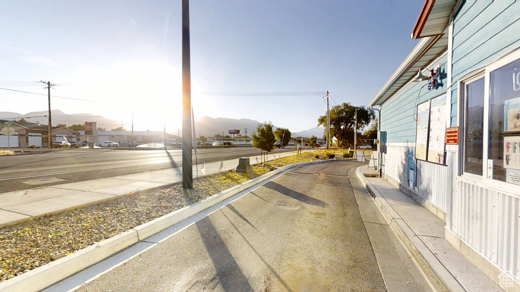 View of asphalt street featuring a mountain view, curbs, and sidewalks