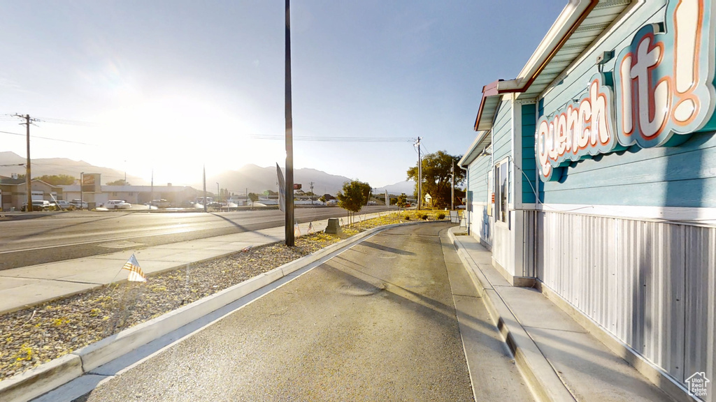 View of asphalt road featuring a mountain view, sidewalks, and curbs