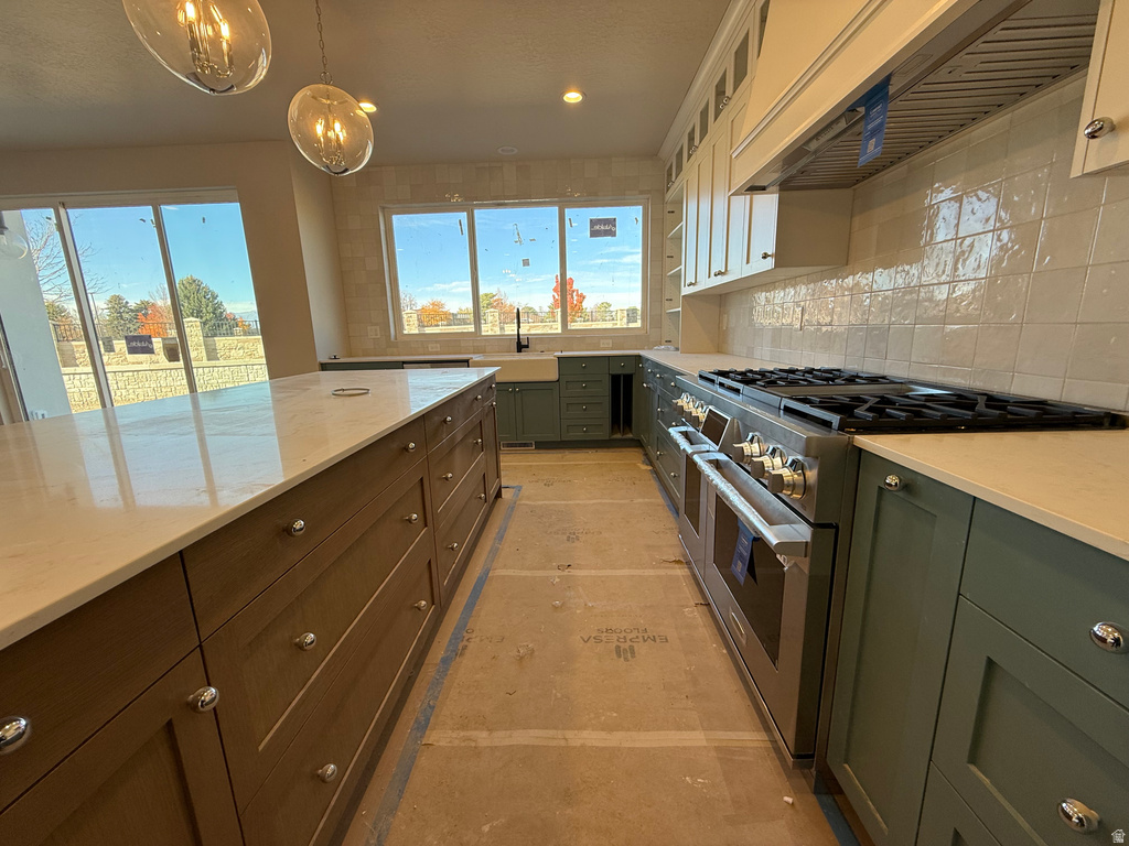 Kitchen featuring range with two ovens, range hood, decorative backsplash, green cabinetry, and glass insert cabinets