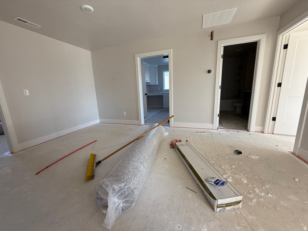 Unfurnished bedroom with ensuite bathroom and a textured ceiling