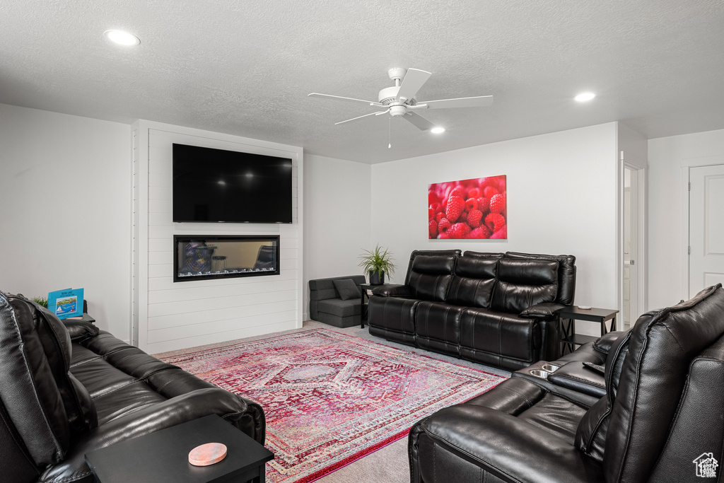 Living area with a textured ceiling, carpet floors, ceiling fan, and recessed lighting