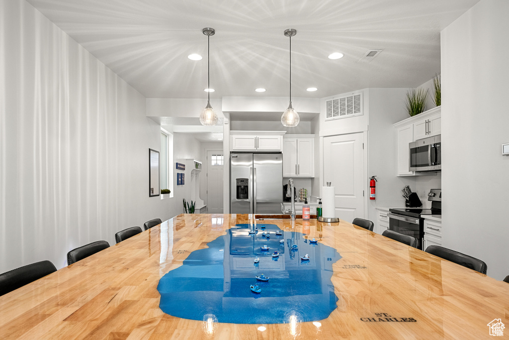 Kitchen with a breakfast bar, white cabinets, recessed lighting, and decorative light fixtures