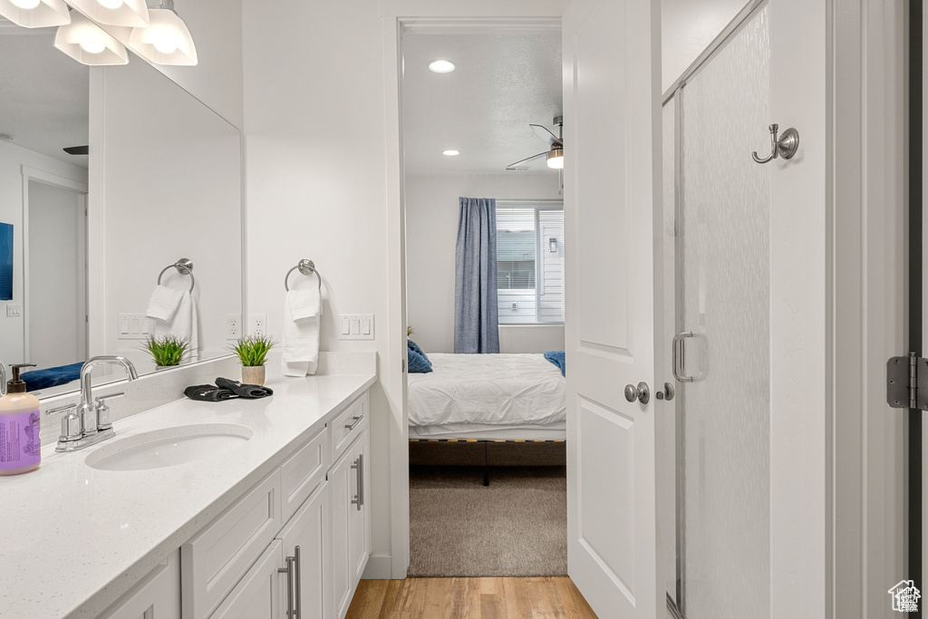 Full bathroom featuring vanity, a shower stall, ensuite bath, light wood-type flooring, and ceiling fan