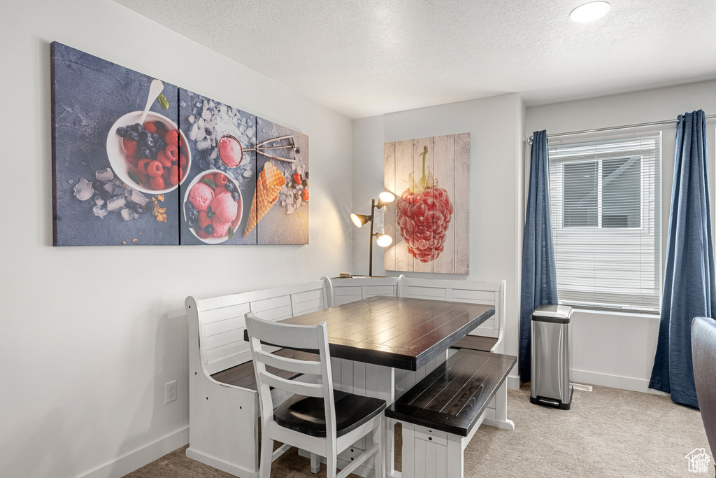 Dining space featuring light carpet and a textured ceiling