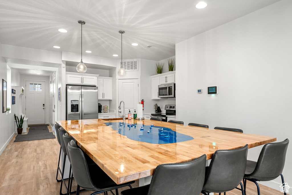 Kitchen featuring a breakfast bar, white cabinetry, recessed lighting, light wood-style flooring, and light countertops