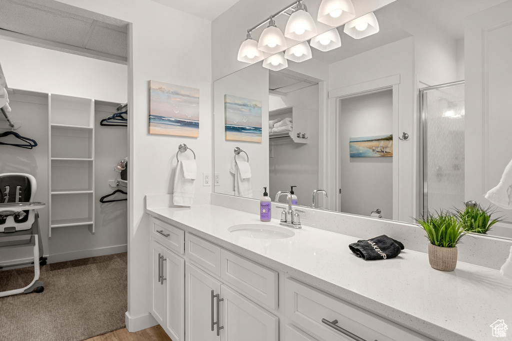 Full bath with a spacious closet, vanity, and a shower stall