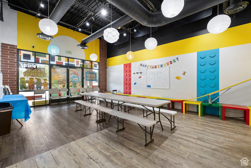 Recreation room with a towering ceiling and hardwood / wood-style flooring