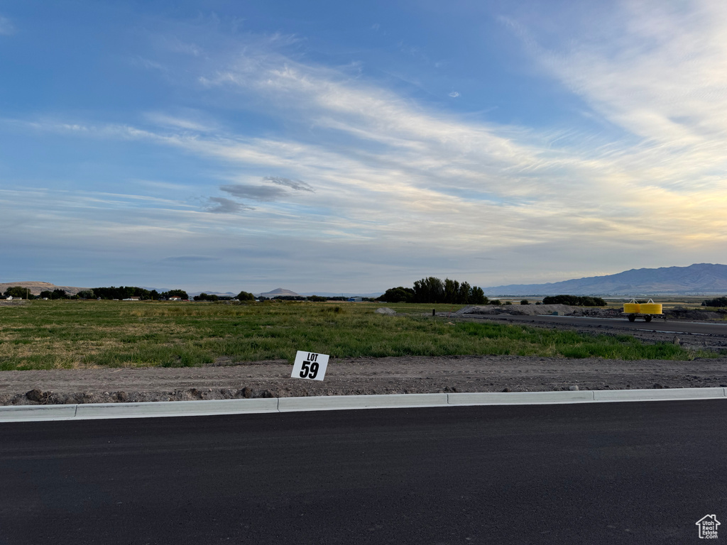 View of asphalt street featuring curbs, a rural view, and a mountain view