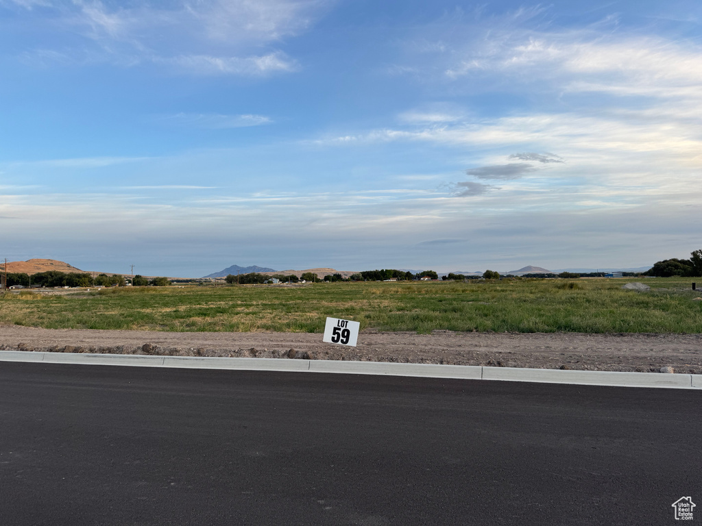 View of asphalt street with curbs, a view of countryside, and a mountain view