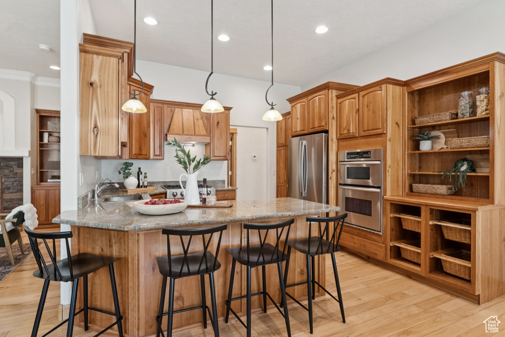 Kitchen featuring a peninsula, light wood-style floors, hanging light fixtures, open shelves, and brown cabinetry