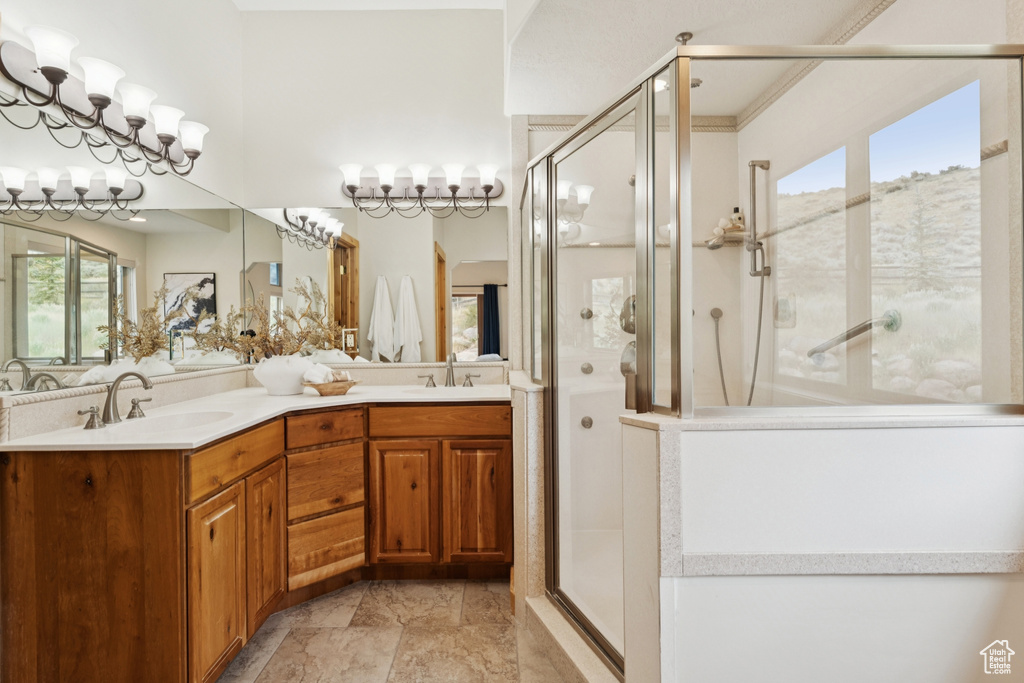 Full bath featuring a stall shower, double vanity, and light stone finish flooring