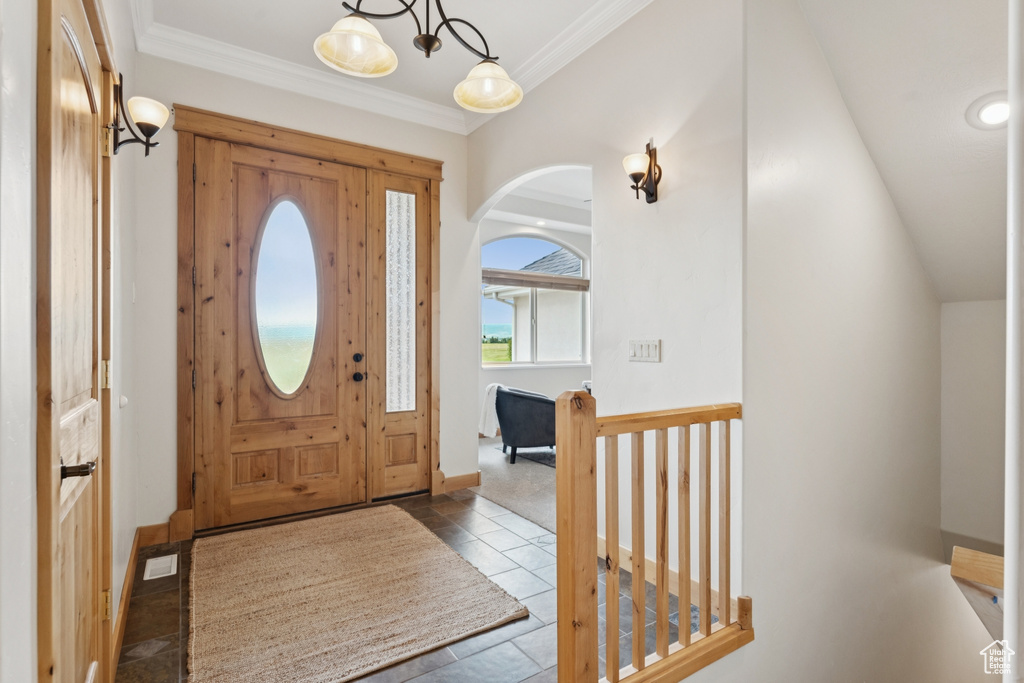 Tiled entrance foyer featuring arched walkways and crown molding