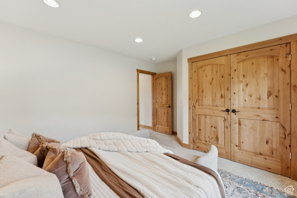 Carpeted bedroom with recessed lighting and a closet