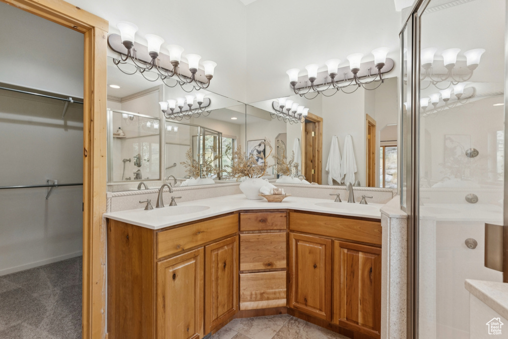 Full bath with a walk in closet, a stall shower, double vanity, and a chandelier