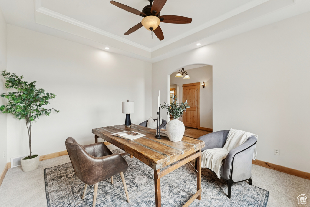 Carpeted office space featuring a tray ceiling, arched walkways, and crown molding
