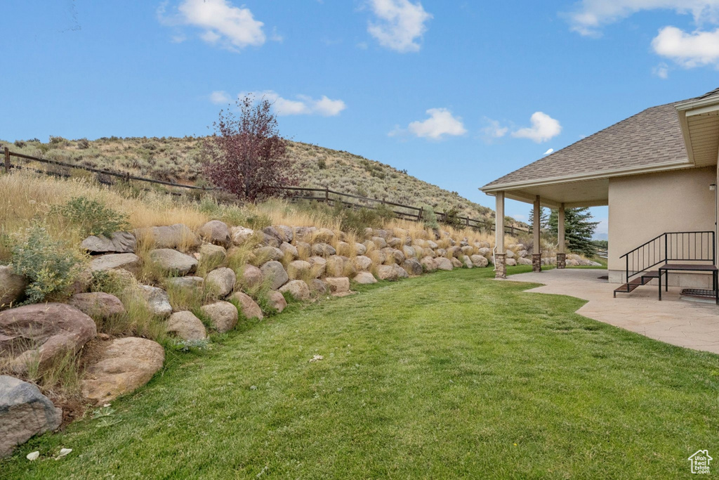View of grassy yard featuring a patio area and a mountain view