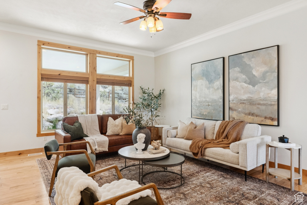Living room featuring ornamental molding, light wood-style flooring, and a ceiling fan