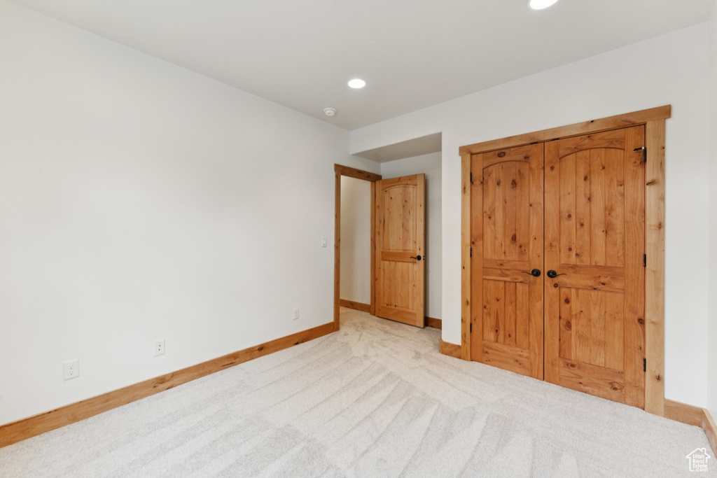 Unfurnished bedroom with light carpet, recessed lighting, and a closet