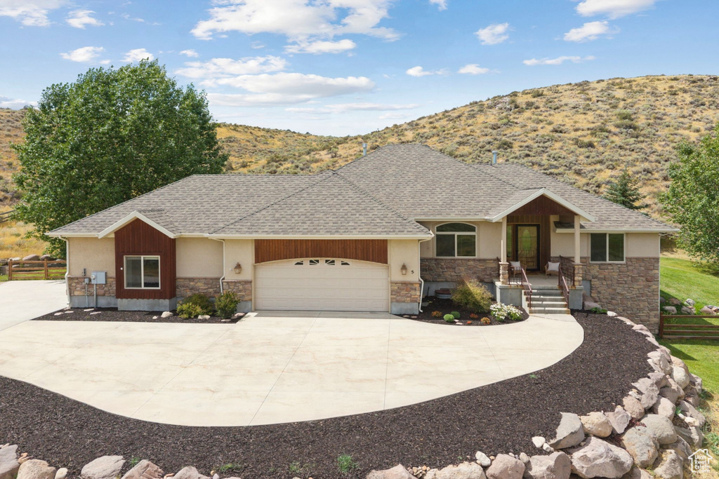 View of front of property featuring concrete driveway, an attached garage, stone siding, roof with shingles, and a porch