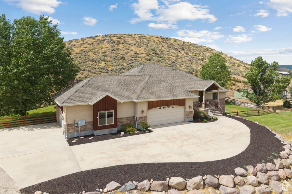 View of front of house with a shingled roof, stone siding, driveway, an attached garage, and a porch