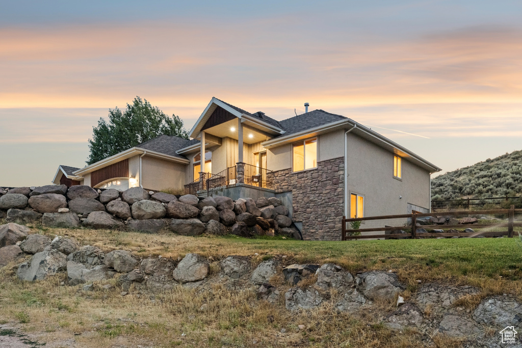View of front of home with a balcony, stone siding, and stucco siding