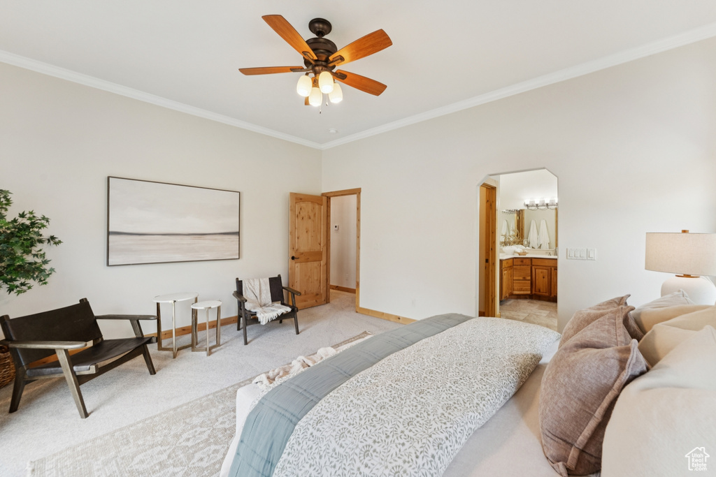 Carpeted bedroom featuring crown molding, ceiling fan, arched walkways, and ensuite bath