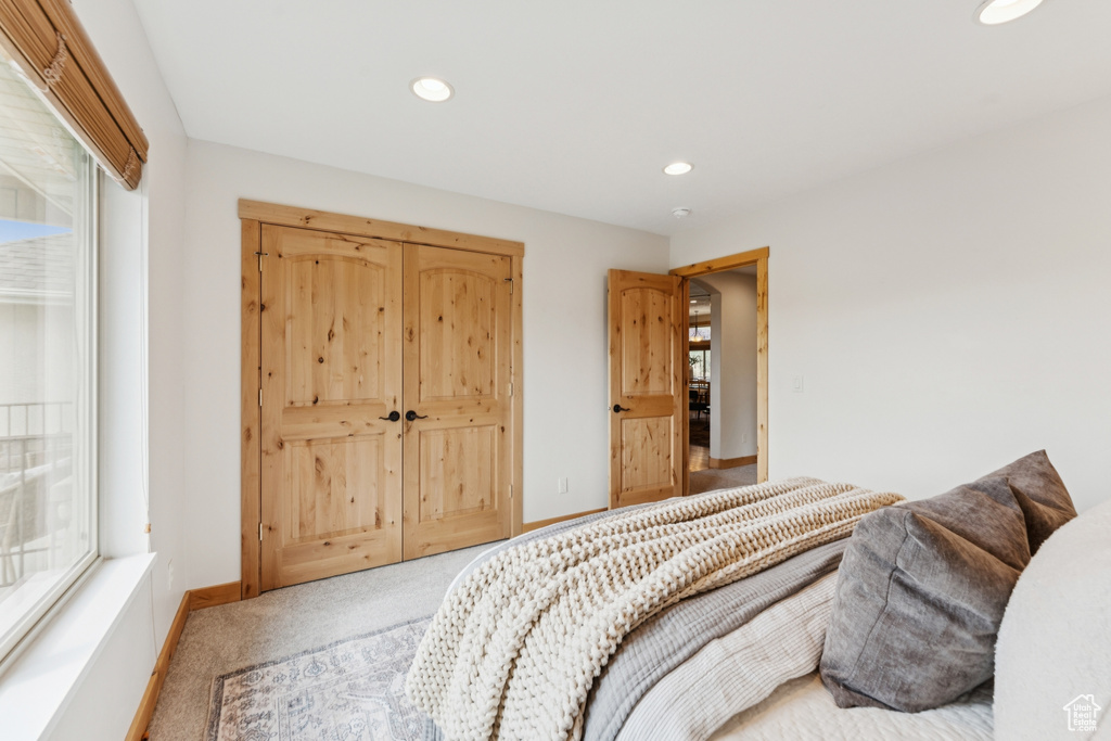 Carpeted bedroom with recessed lighting and a closet