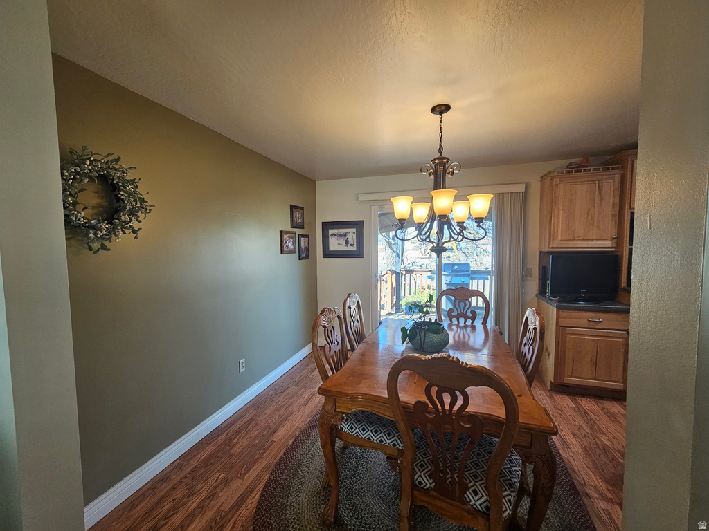 Dining space featuring dark wood-style flooring and a chandelier