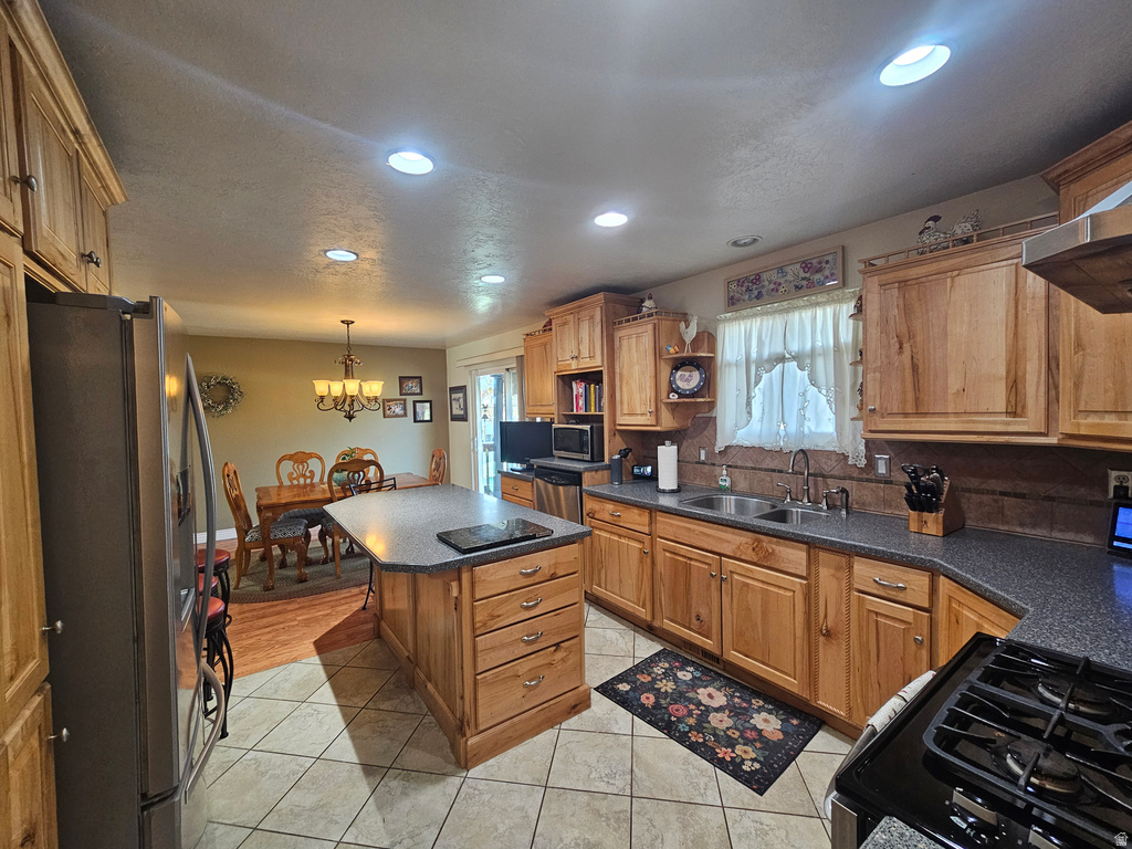 Kitchen featuring appliances with stainless steel finishes, dark countertops, recessed lighting, light tile patterned floors, and a center island