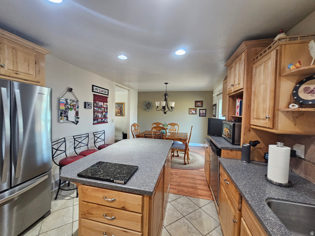 Kitchen with stainless steel appliances, a kitchen island, recessed lighting, decorative light fixtures, and a chandelier