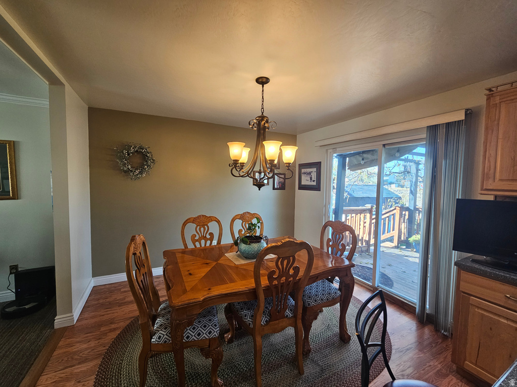 Dining area with dark wood-type flooring and a chandelier