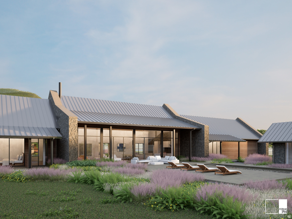 Expansive contemporary residence featuring a stone and wood facade, corrugated metal roofing, and floor-to-ceiling windows