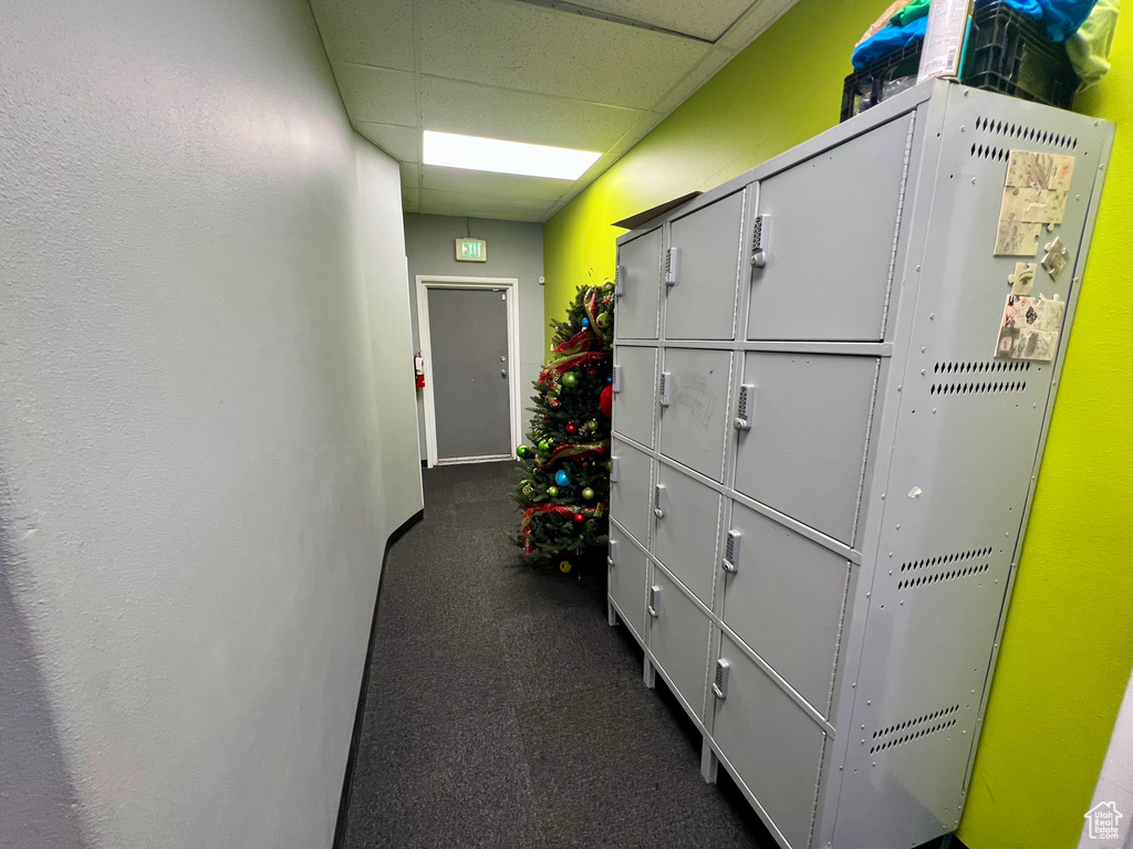 Hall with a paneled ceiling and dark colored carpet