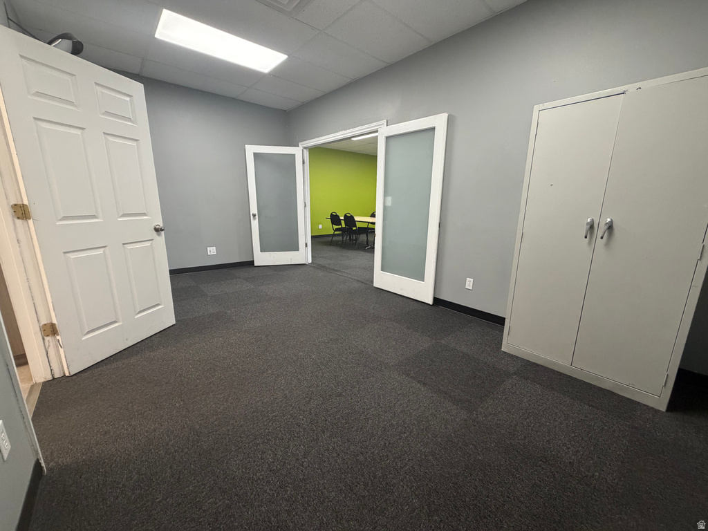 Spacious room featuring neutral gray walls and dark carpet tile flooring